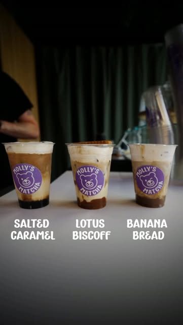 Drei Specialty Iced Latte im Becher mit Bär-Sticker, beschriftet mit Salted Caramel, Lotus Biscoff und Banana Bread